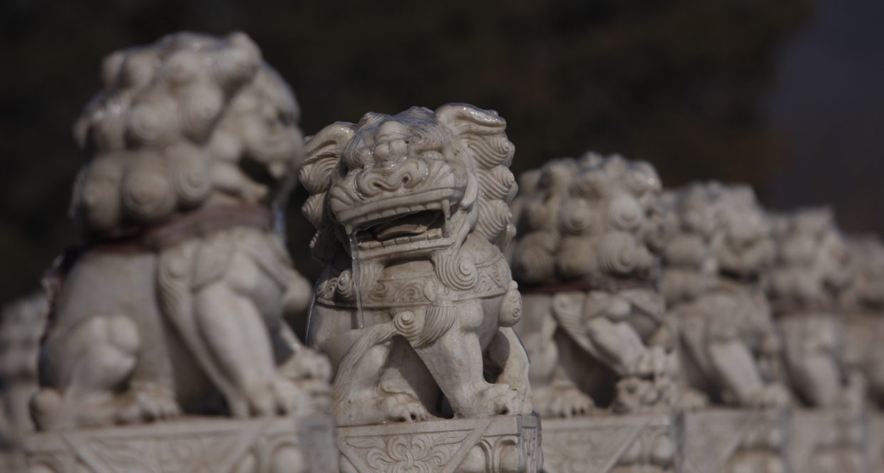 A group of chinese statues of lions face to the right away from the camera except for one that faces the camera. Photo by MC-Pictures/CC-BY