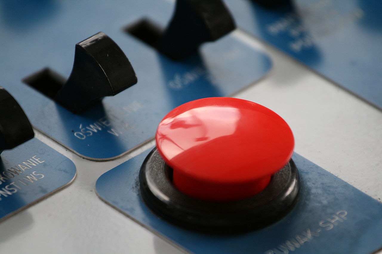 [IMAGE] A large red button in front of a series of switches