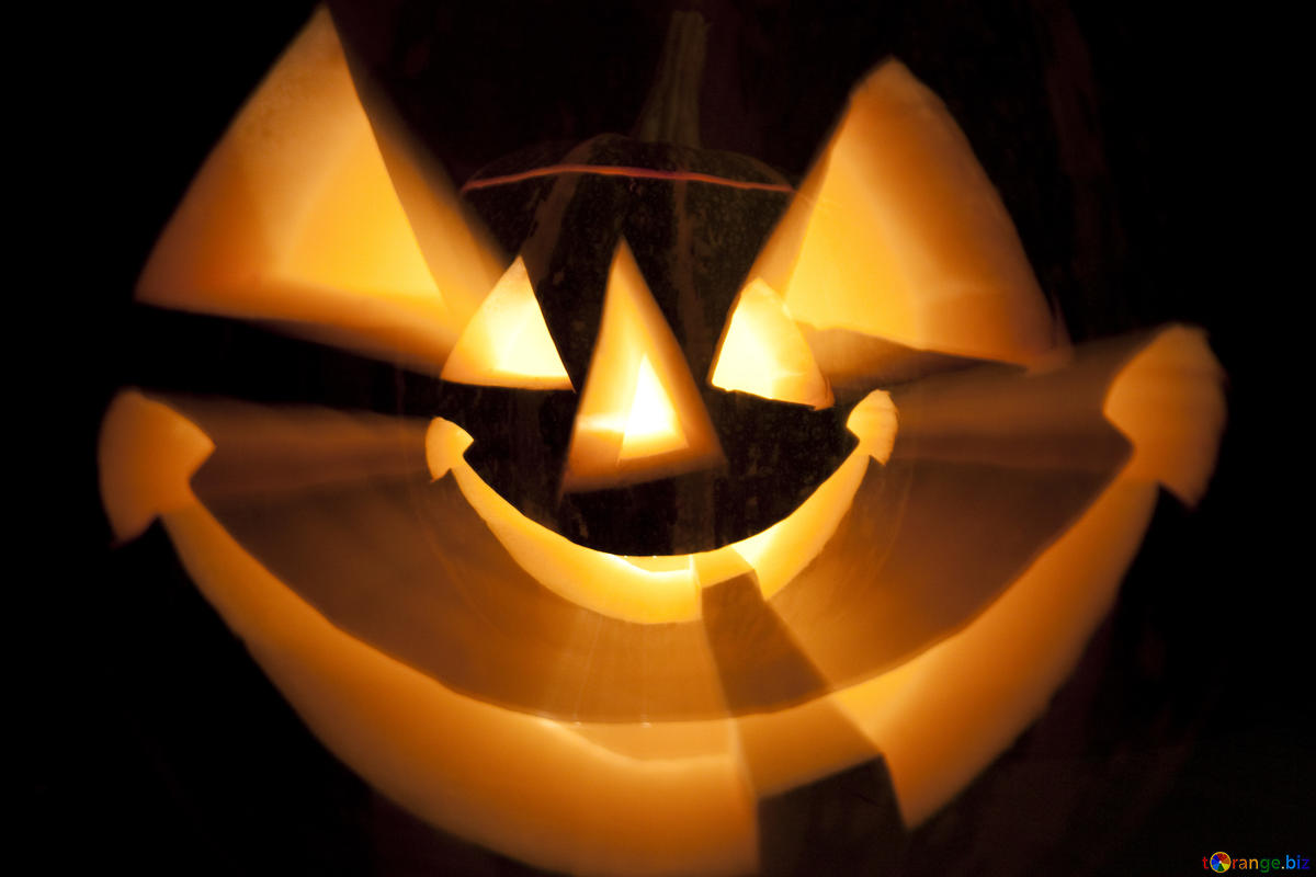 A photo composite of a smiling halloween pumpkin carving of a face, with its face superimposed larger over the original face